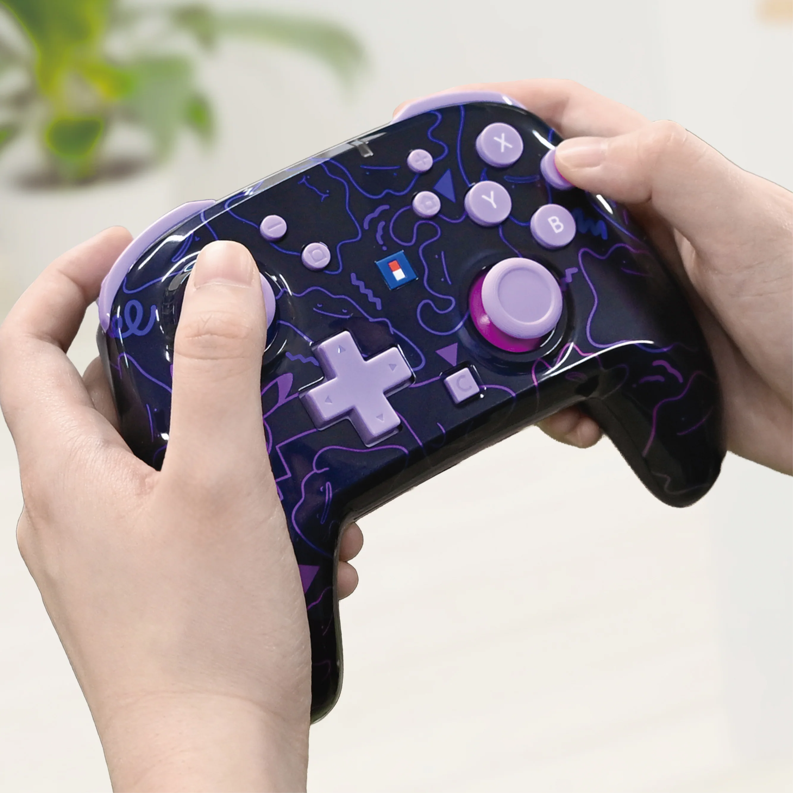Hände halten einen schwarzen Videospiel-Controller mit lila Mustern und Tasten.