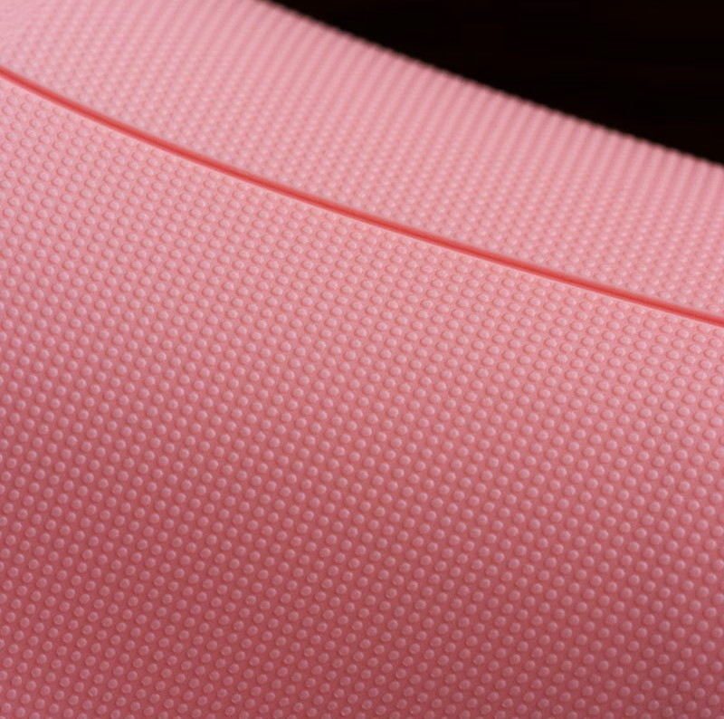 Nahaufnahme einer rosa Oberfläche mit feinem Punktmuster und einer leichten Vertiefungslinie.