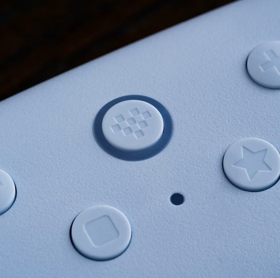 Nahaufnahme eines hellblauen Geräts mit runden Tasten, die Symbole für ein kariertes Muster, einen Stern und ein Quadrat zeigen.