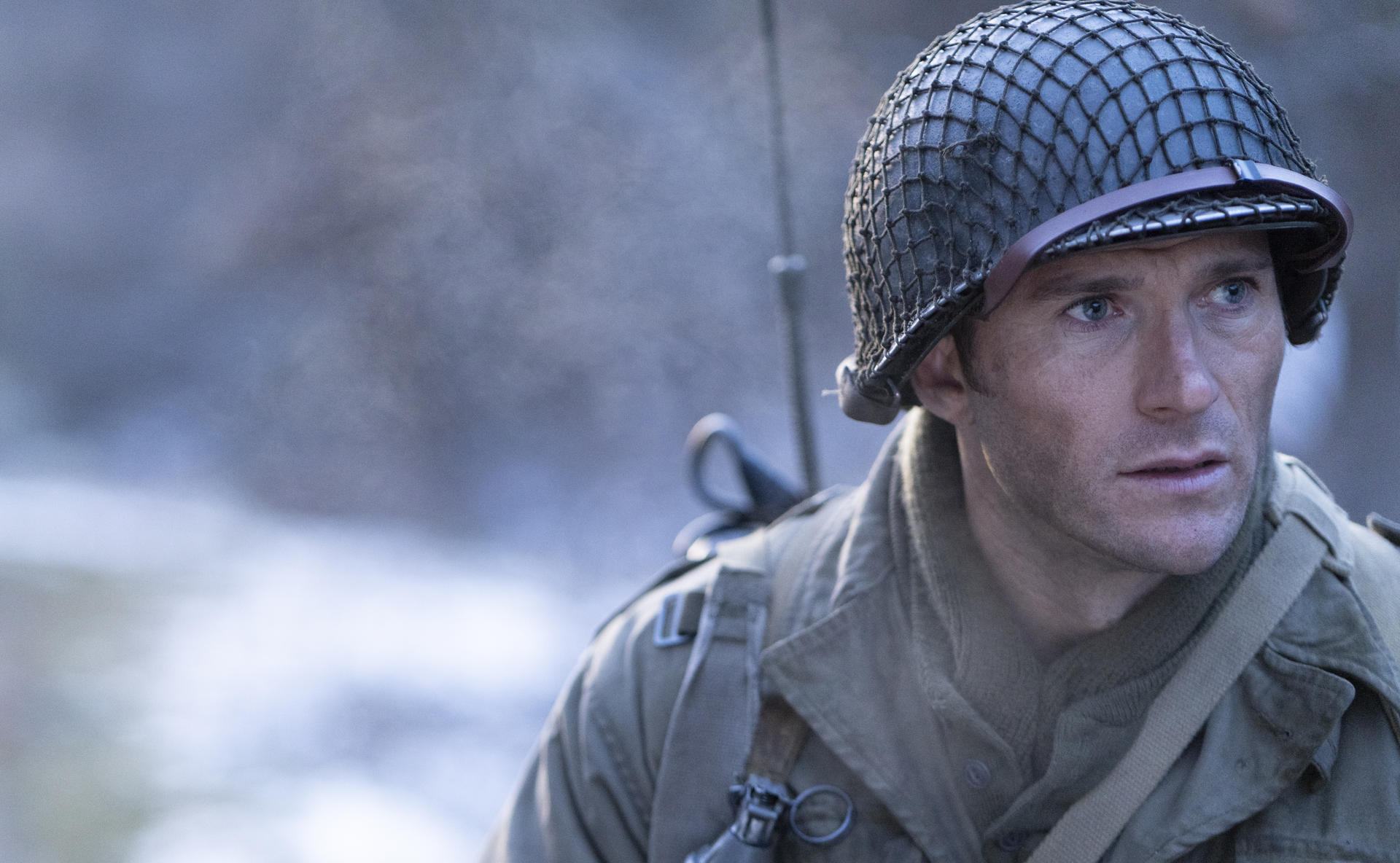 Ein Soldat mit Helm und Uniform blickt besorgt in die Ferne vor einem verschwommenen Hintergrund.