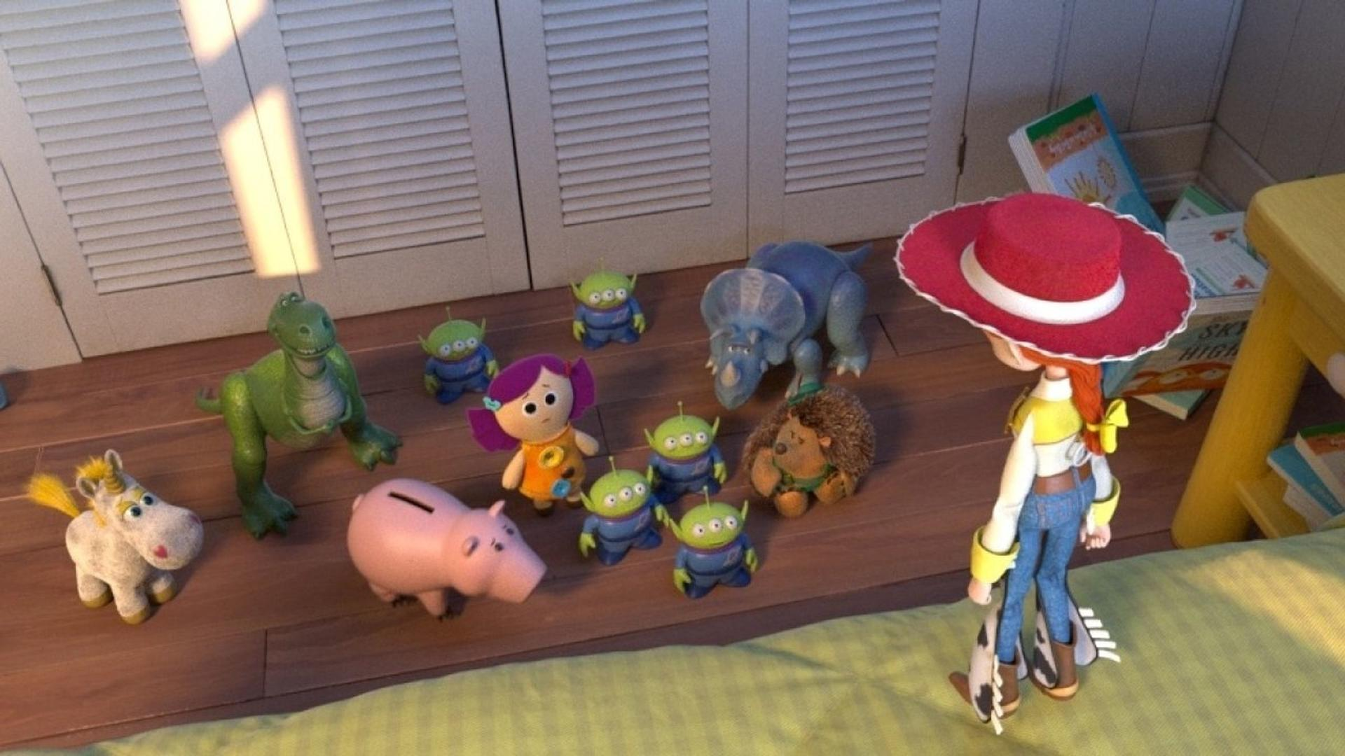 Jessie steht im Zimmer und schaut auf verschiedene Spielzeuge wie Rex, Hamm, einen Triceratops und mehrere kleine Aliens.