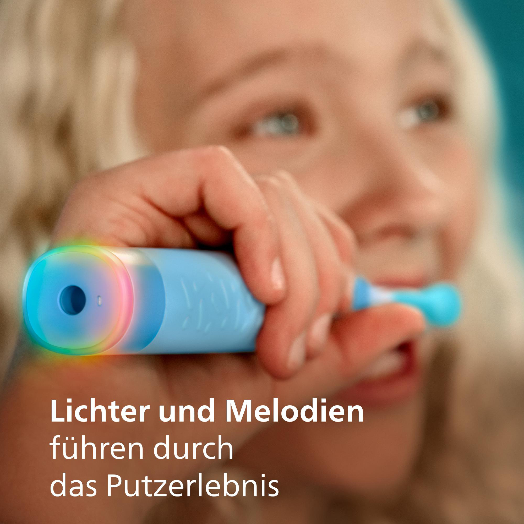 Ein Kind hält eine blaue elektrische Zahnbürste mit bunten Lichtern am Griff.