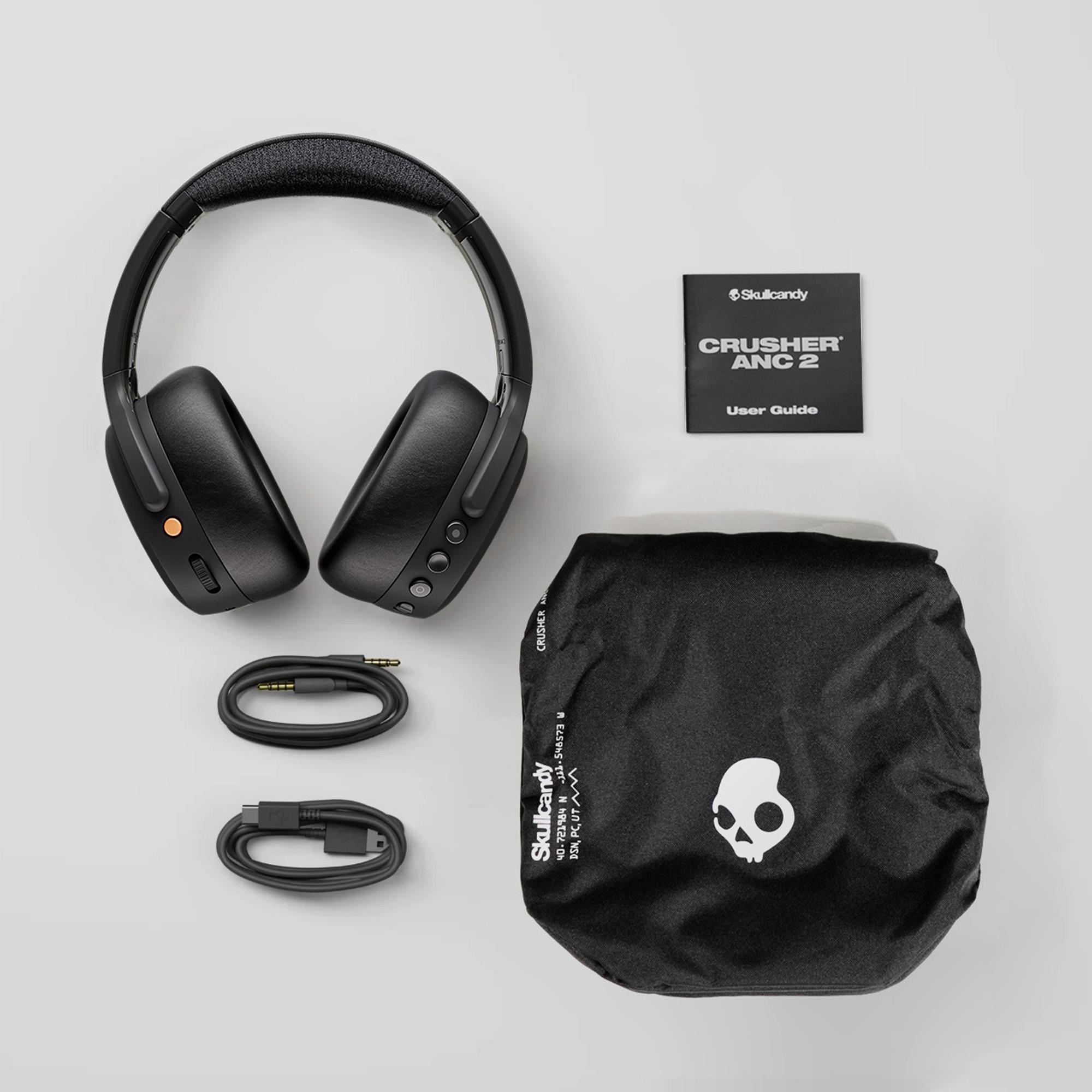 Schwarze Skullcandy Crusher ANC 2 Kopfhörer mit Etui, Kabeln und Handbuch auf hellem Grund.