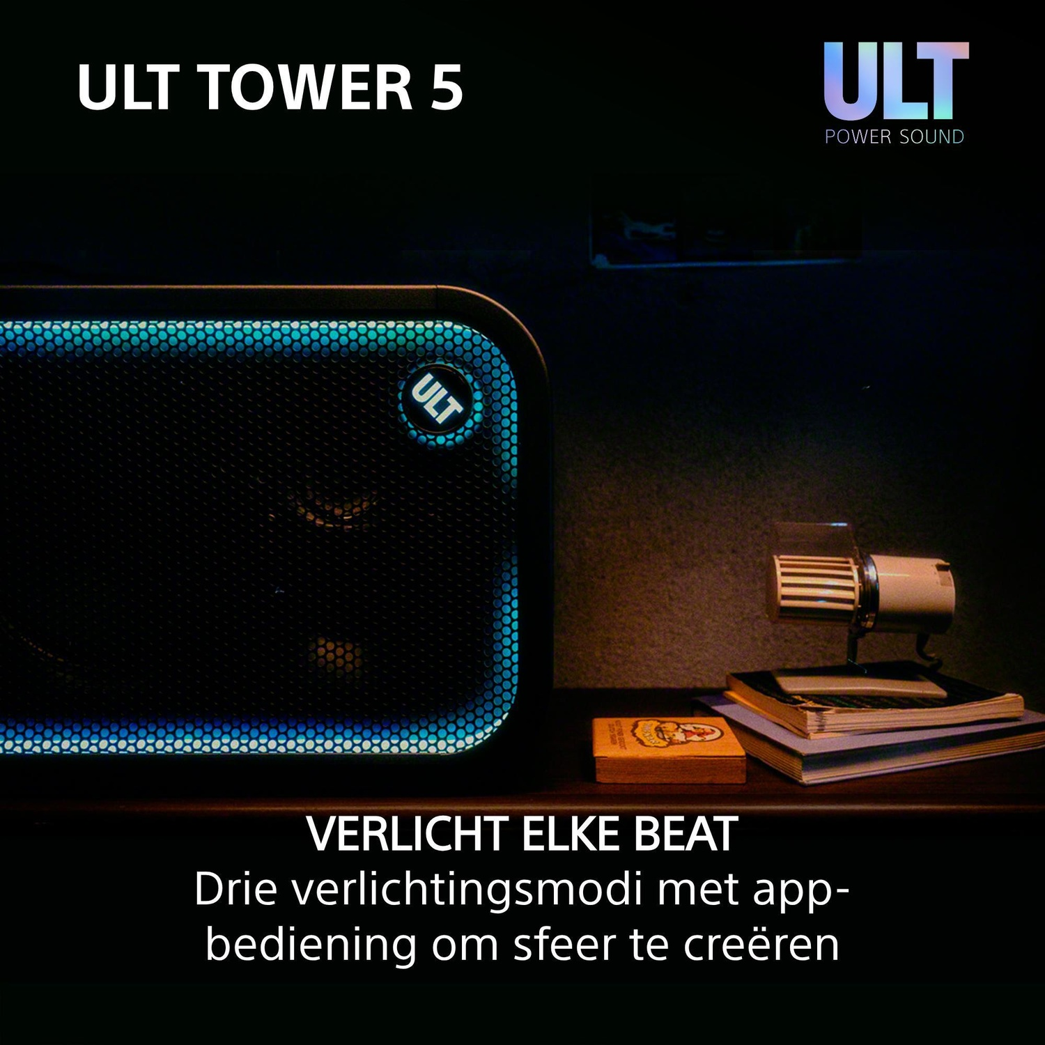 A black ULT Tower 5 speaker with blue glowing lights sits on a dark wooden surface with books.