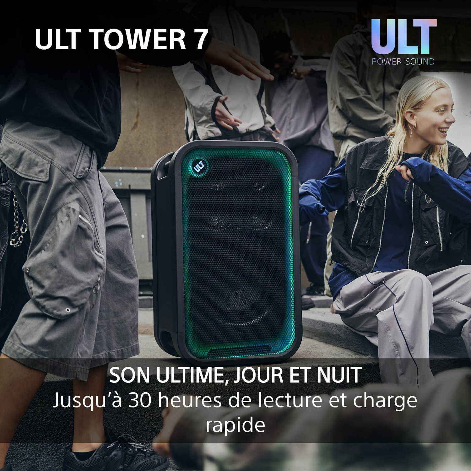 Un grand haut-parleur ULT Tower 7 noir avec une lumière verte, entouré de personnes qui dansent.