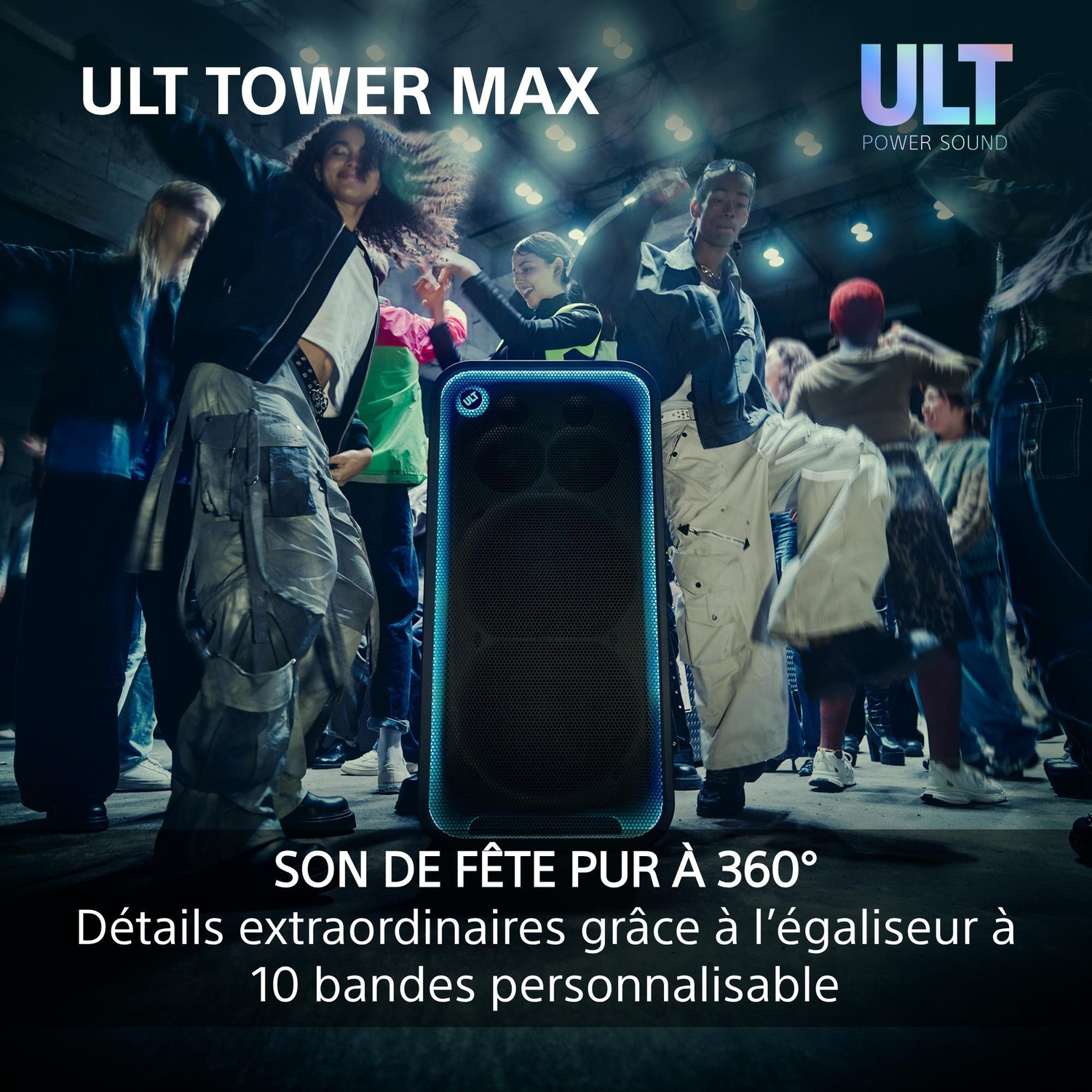 Un groupe de jeunes danse joyeusement autour d'une grande enceinte de fête illuminée en bleu dans une pièce.