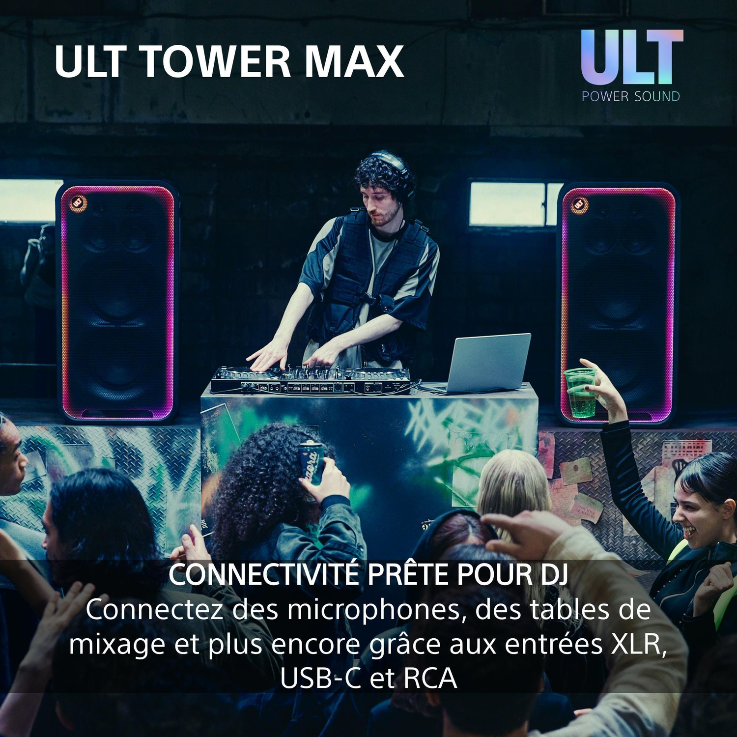 Un DJ mixe de la musique, entouré de deux grandes enceintes LED devant une foule dansante.
