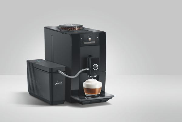 Schwarze Jura Kaffeemaschine mit Milchbehälter und einer Tasse Cappuccino.