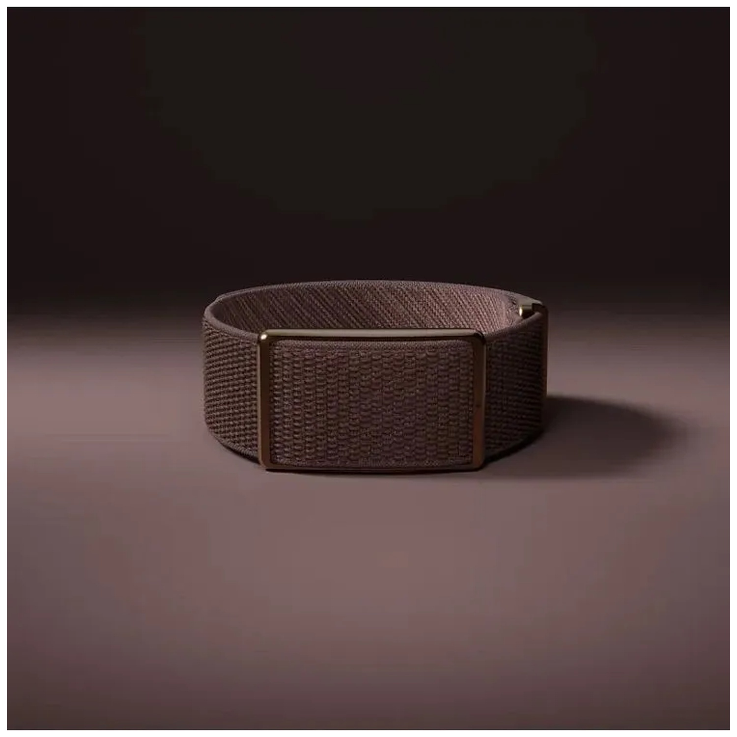 A brown woven watch band with a gold buckle on a dark background.