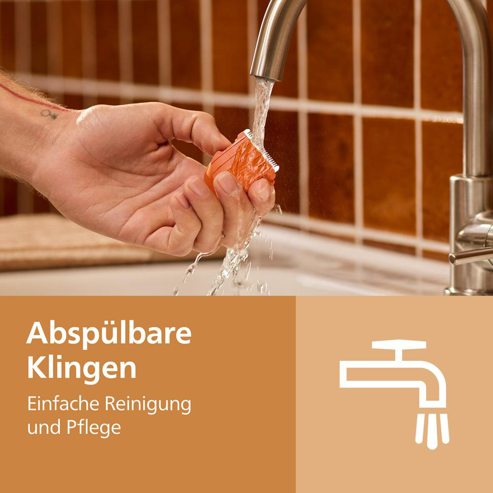 Eine Hand wäscht einen orangen Rasierkopf unter einem fließenden Wasserhahn.
