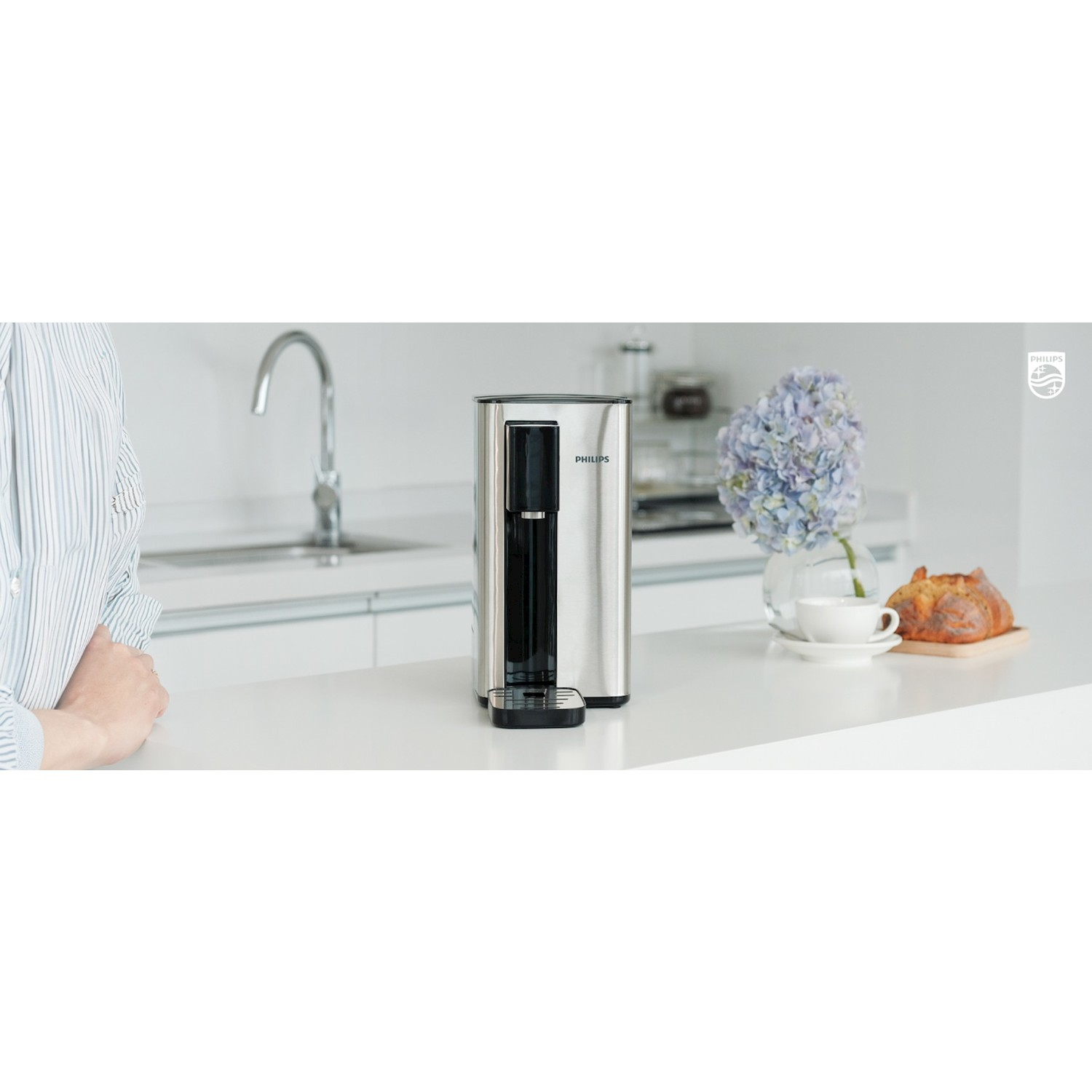 Una macchina da caffè Philips su un bancone da cucina con fiori e pane sullo sfondo.
