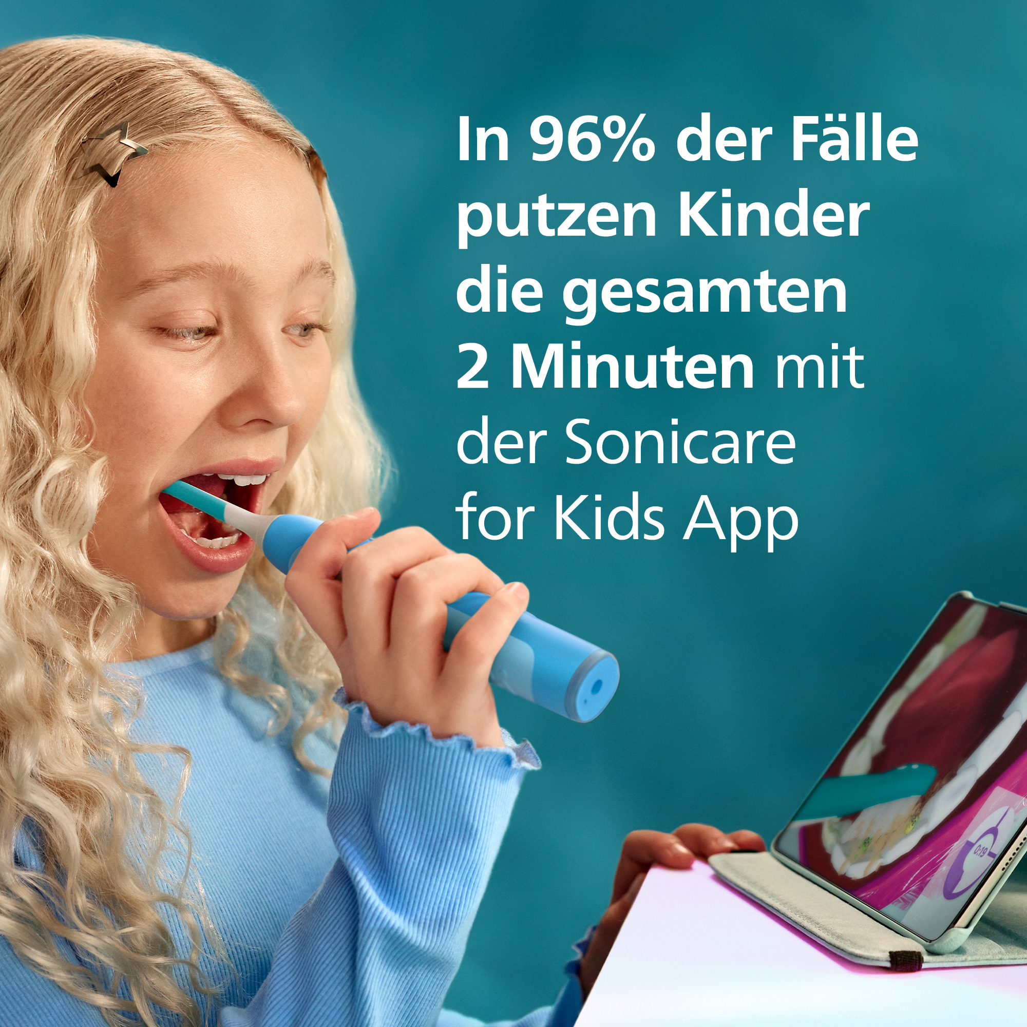 Una bambina bionda si lava i denti con uno spazzolino blu Sonicare guardando un tablet.