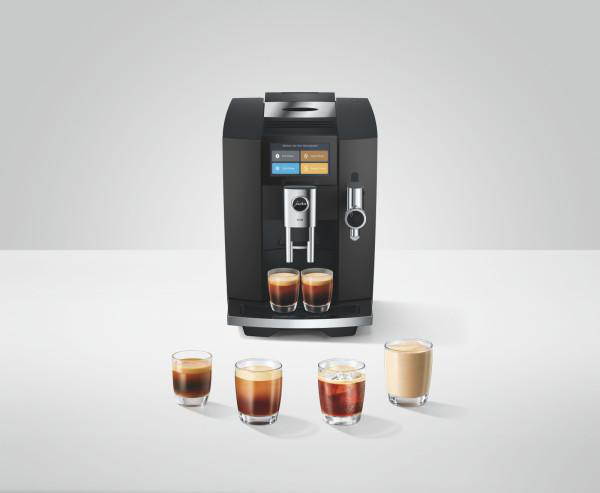 Schwarze Kaffeemaschine auf weißem Tisch mit verschiedenen Gläsern Kaffee und Getränken.