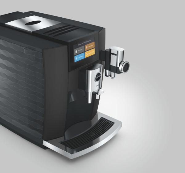 Moderne schwarze Kaffeemaschine mit Touchscreen, verchromtem Auslauf und integrierter Milchdüse auf hellem Hintergrund.