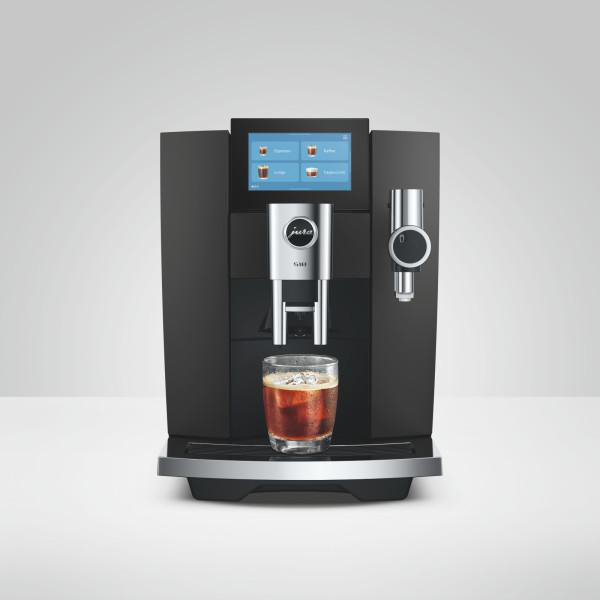 Moderne schwarze Kaffeemaschine mit Touchscreen und gefülltem Glas.