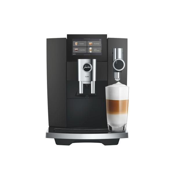 Schwarze Jura-Kaffeemaschine mit Display und einem Glas Latte Macchiato davor.