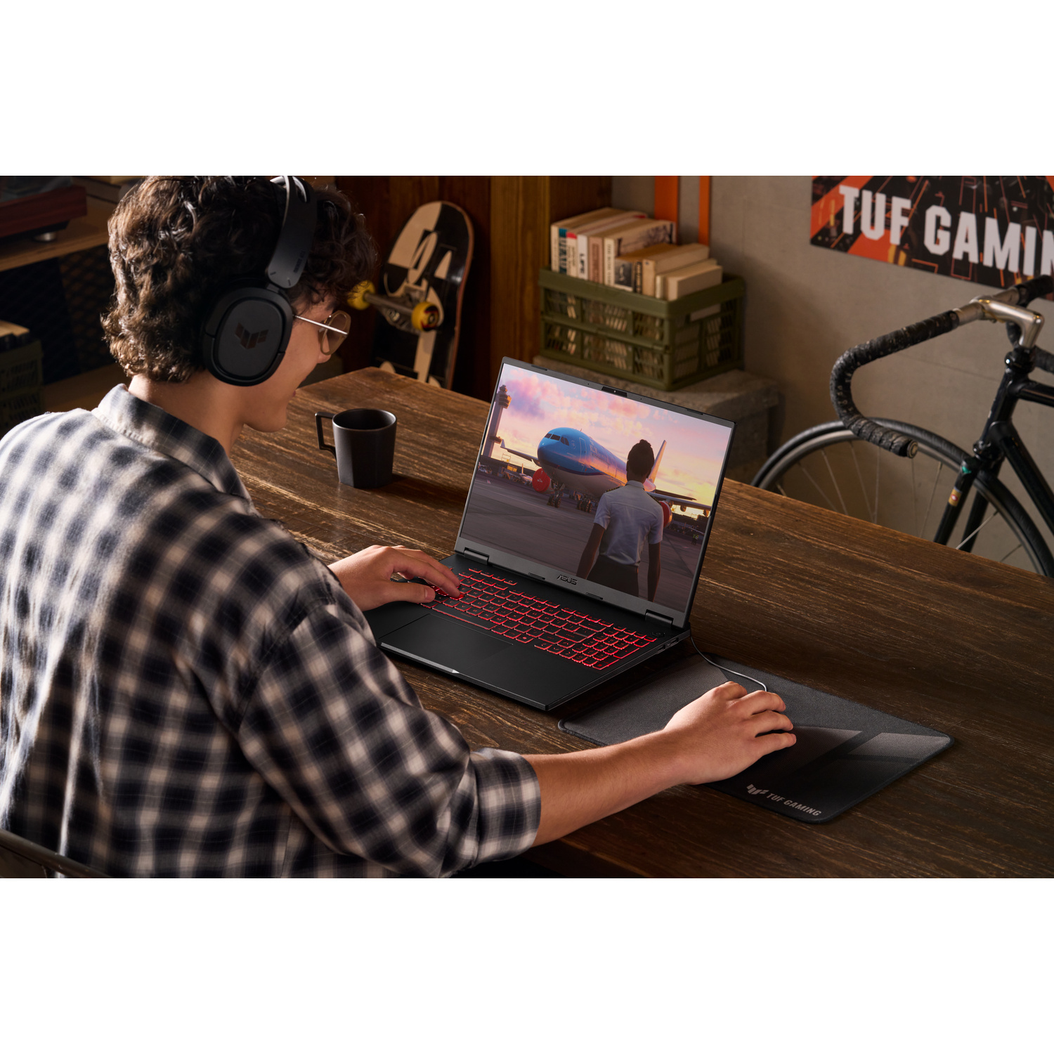 Persona in camicia a quadri a una scrivania in legno usa laptop da gaming e mouse, con gioco di aerei sullo schermo.