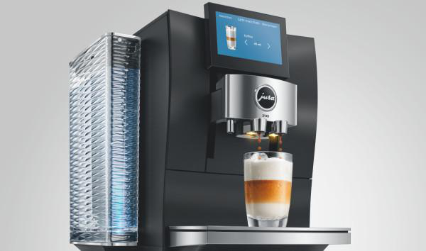 Moderne schwarze Kaffeemaschine mit Wassertank, Display und Glas mit Latte Macchiato.
