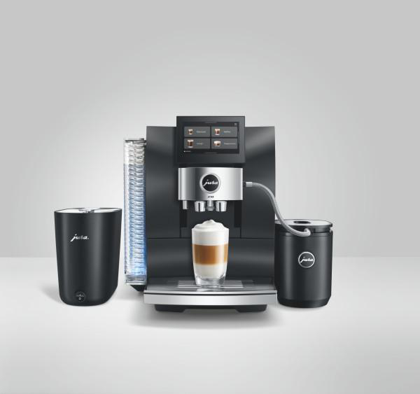 Moderne schwarze Jura Kaffeemaschine mit Display, Milchbehälter und einer fertigen Tasse Latte Macchiato.