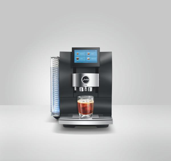 Moderne schwarze Kaffeemaschine mit Touchscreen und einem Glas Eiskaffee auf dem Tablett.