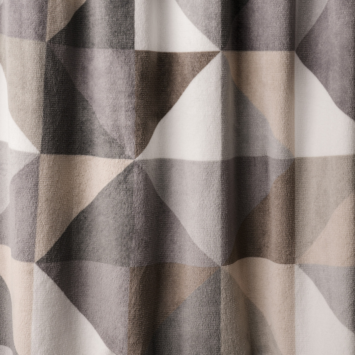 Motivo geometrico di triangoli in grigio, marrone, beige e bianco su tessuto texturizzato.