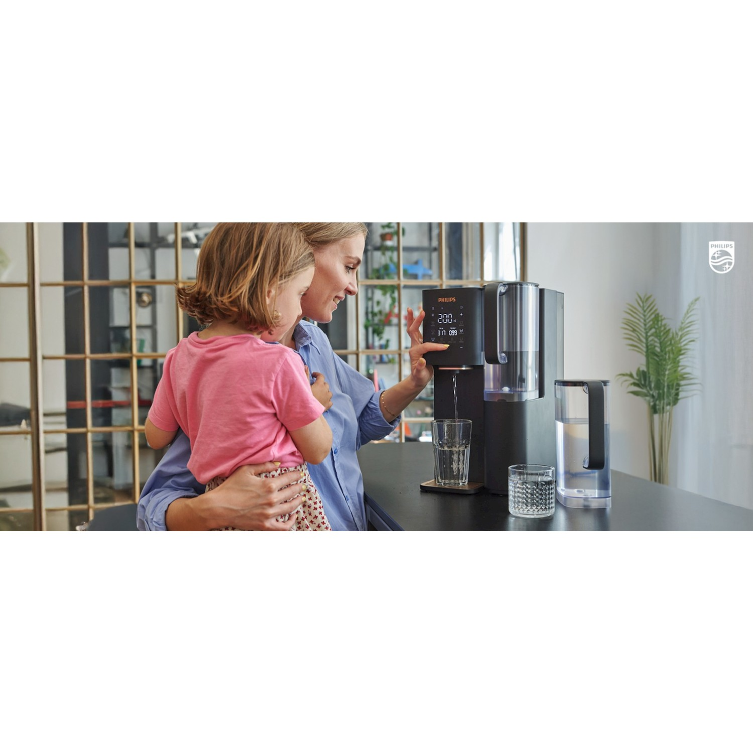 Una donna con un bambino usa un erogatore d'acqua nero Philips su un bancone.