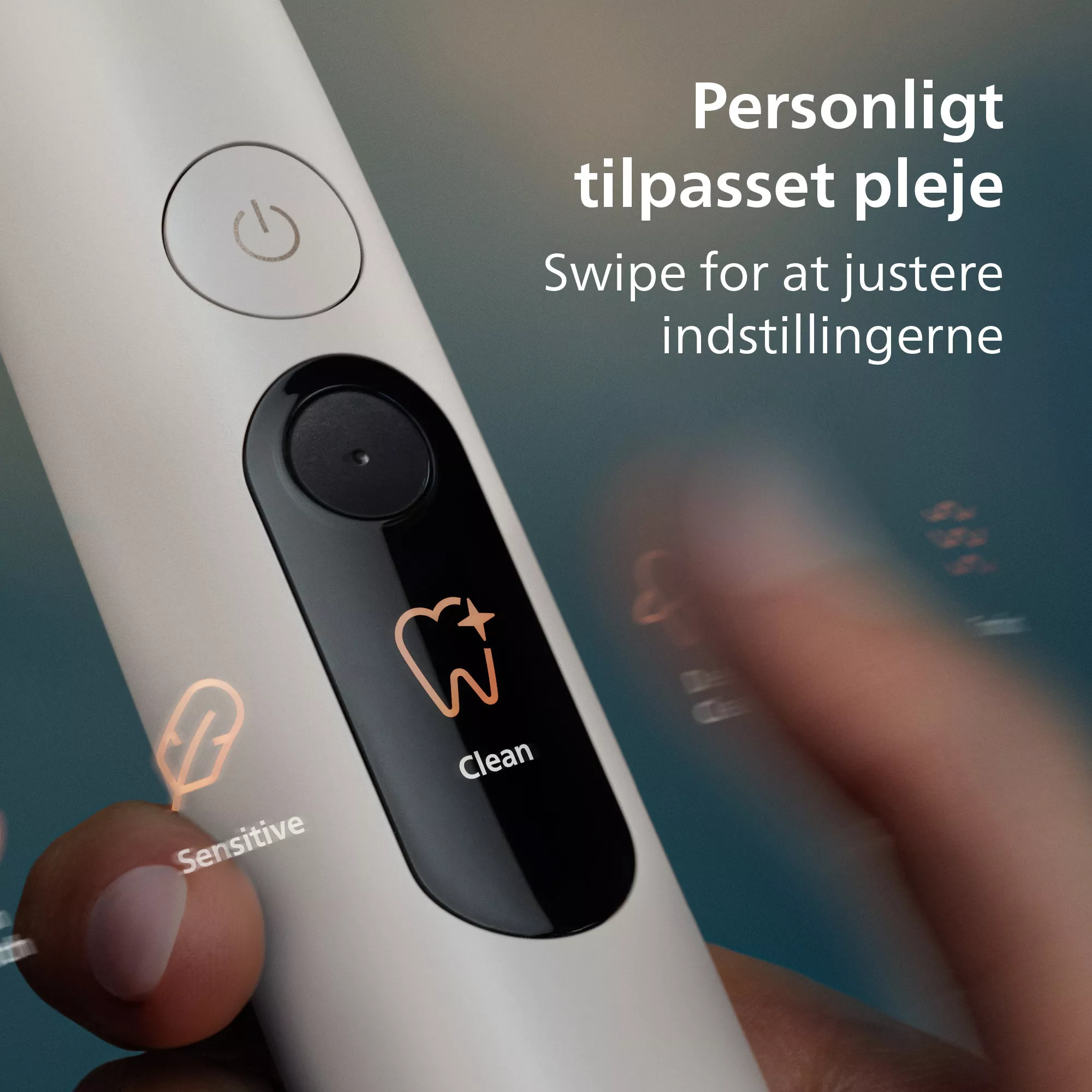Egy ujj húz egy fehér elektromos fogkefén, tiszta és érzékeny üzemmód ikonokat mutatva a kijelzőn.