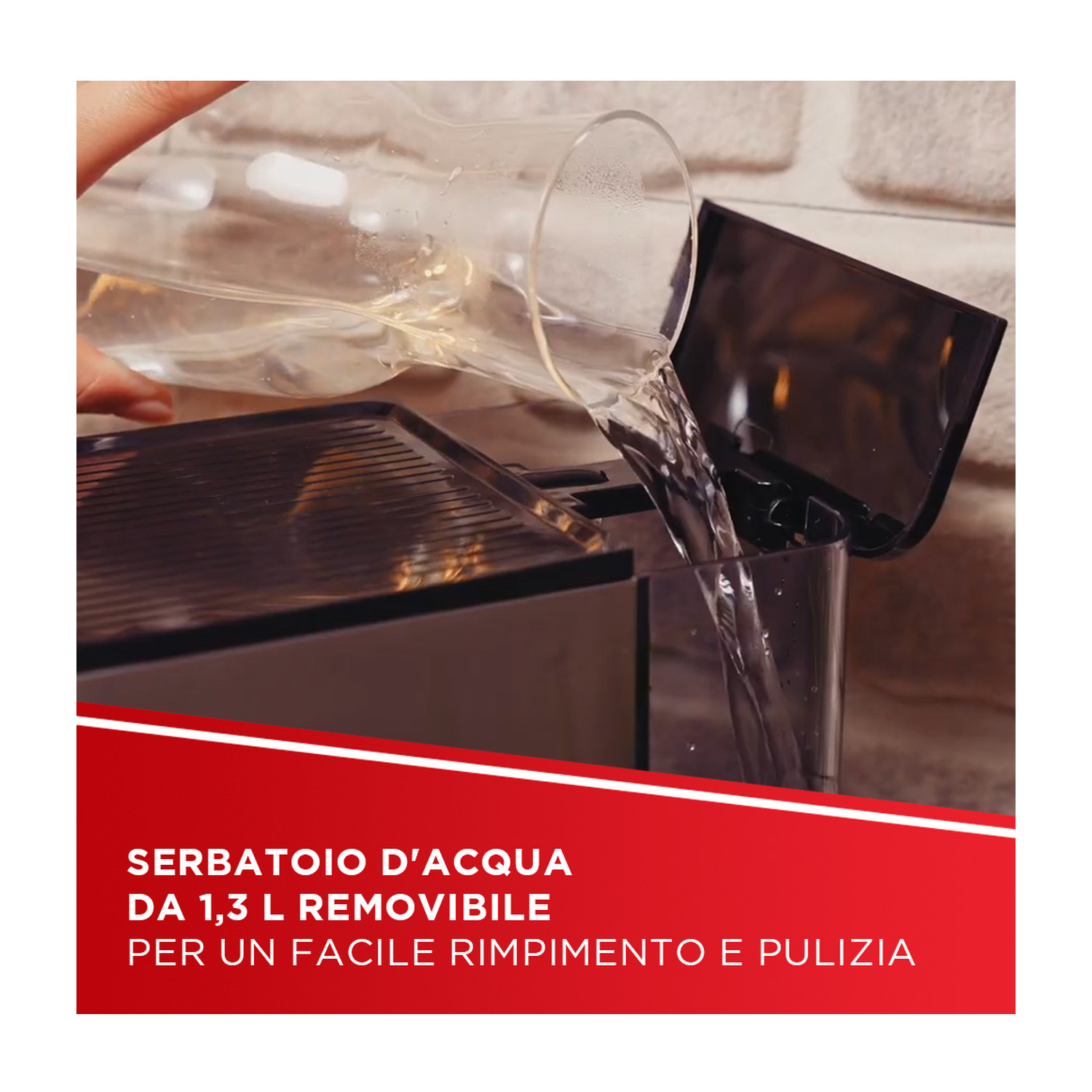 L'acqua viene versata da una caraffa di vetro nel serbatoio di una macchina da caffè.