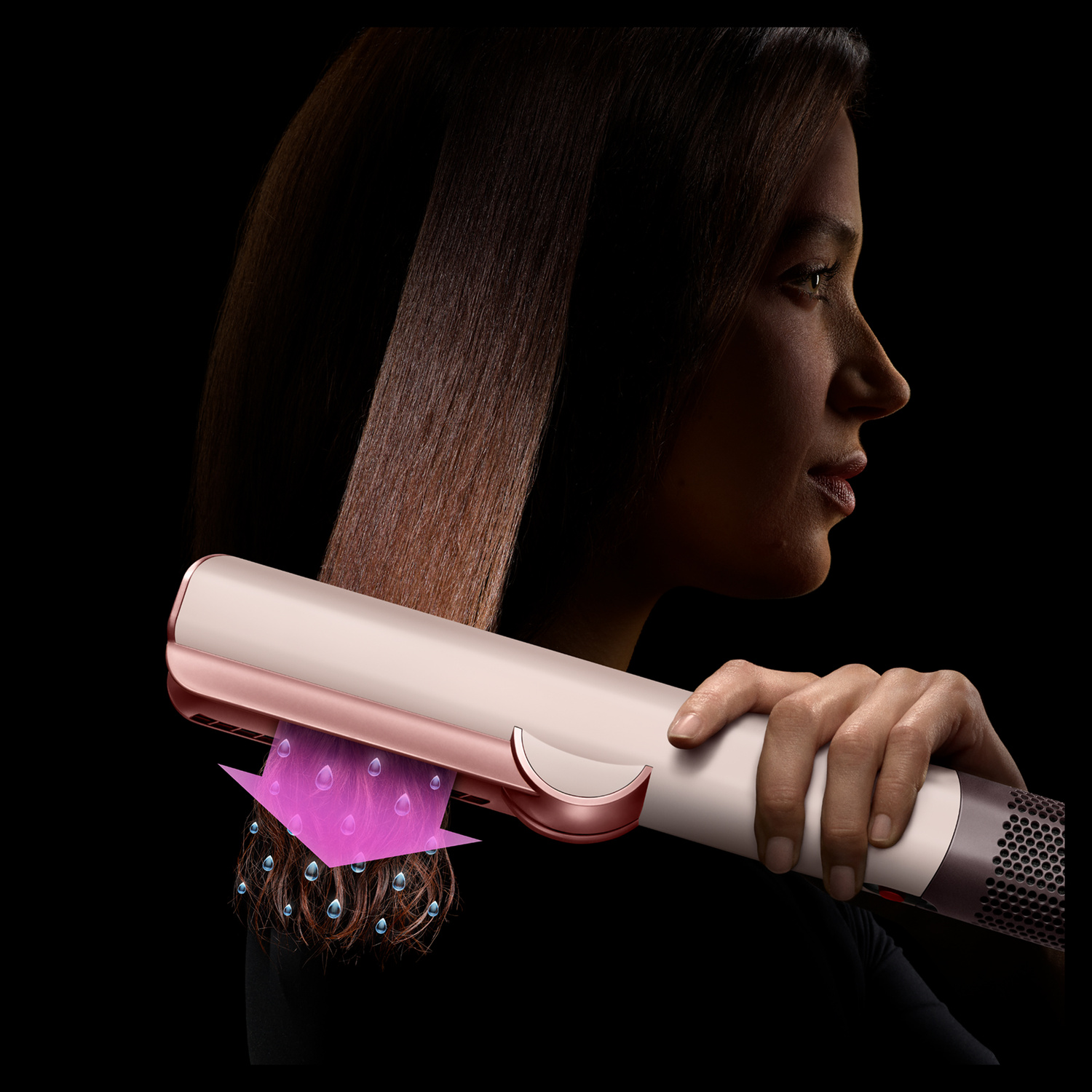 Una donna tiene in mano uno strumento per capelli che liscia i capelli bagnati, rilasciando goccioline d'acqua.