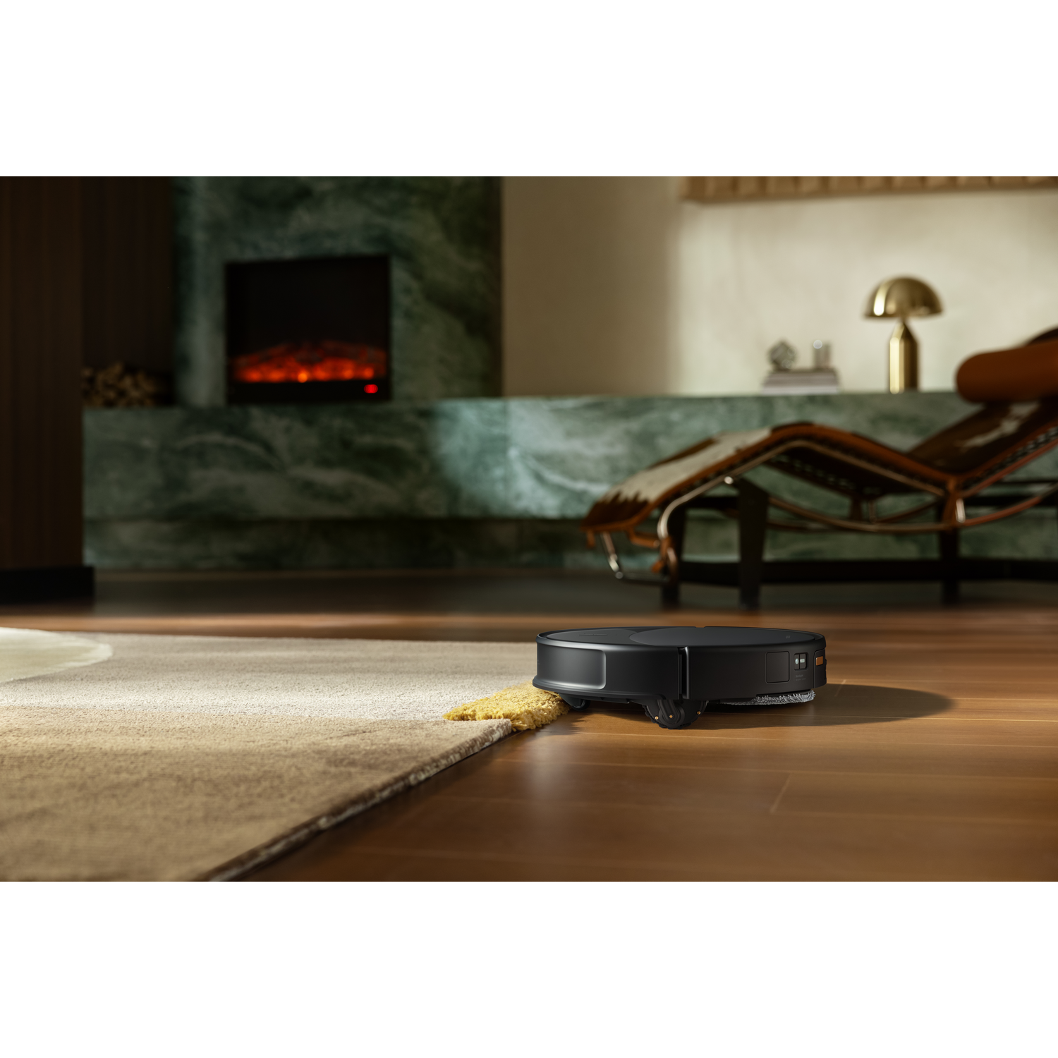 Un robot aspirateur noir sur un sol en bois à côté d'un tapis dans un salon moderne et chaleureux.