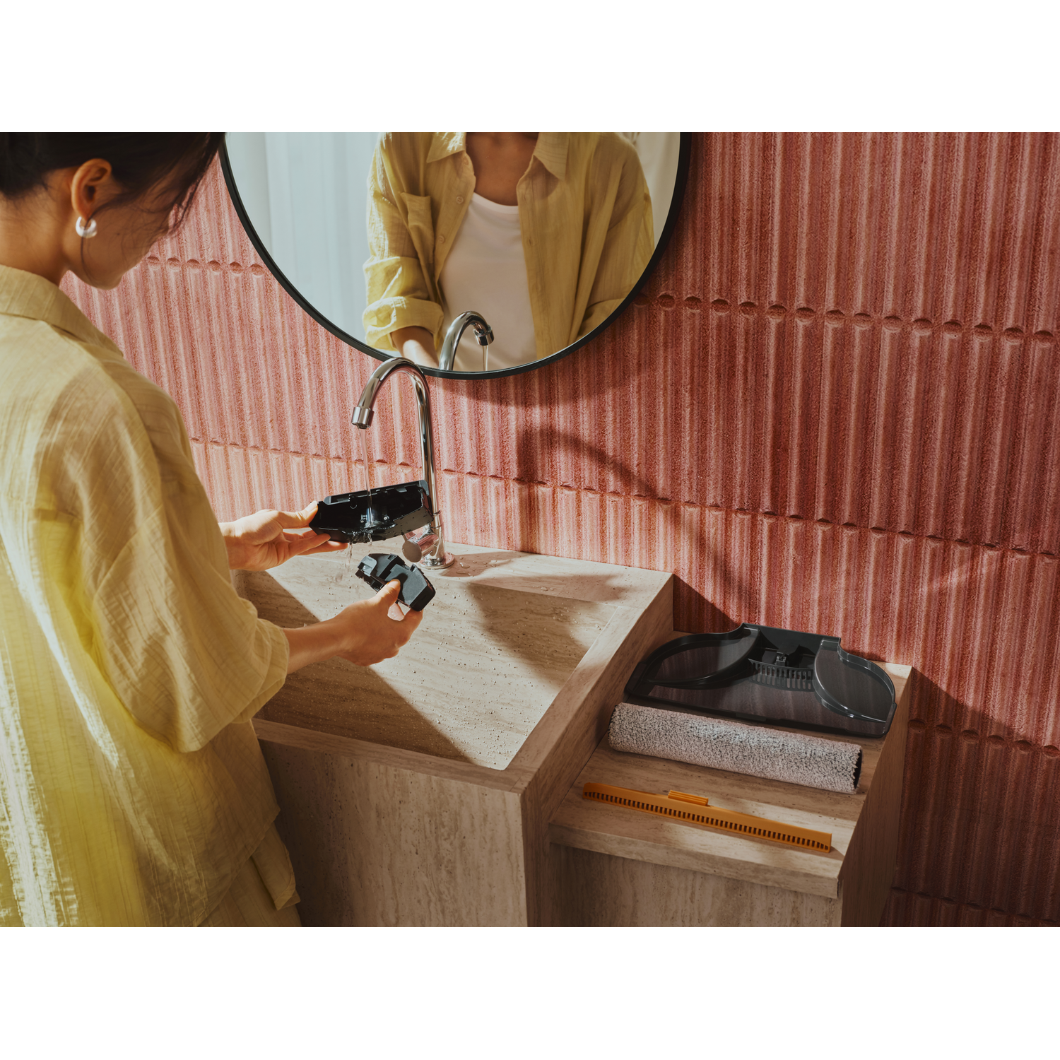 Une femme lave des pièces de robot dans un lavabo rose.