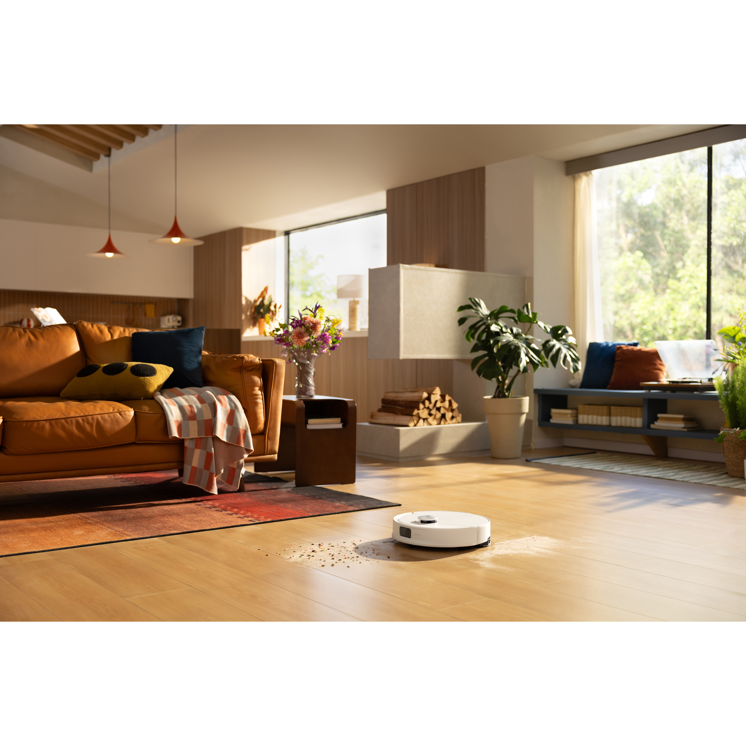 Un robot aspirateur nettoie un plancher en bois dans un salon moderne et ensoleillé avec un canapé en cuir.