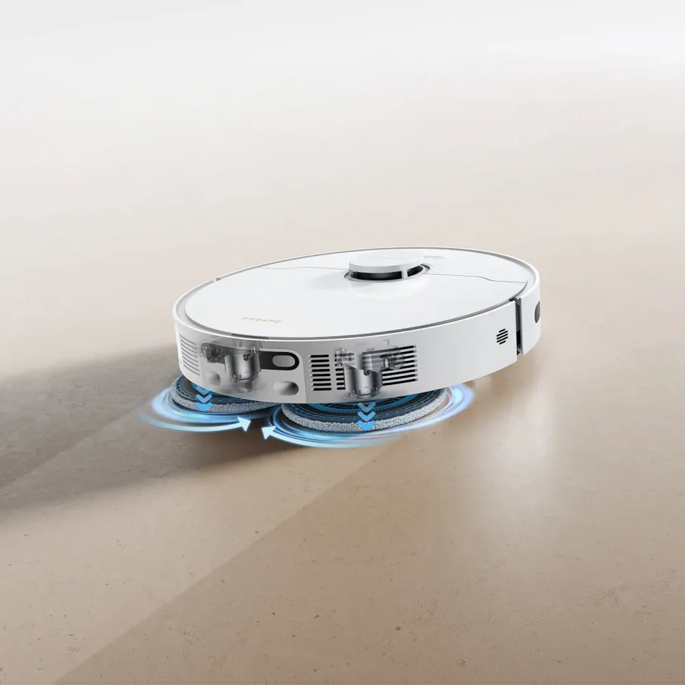 Fehér robotporszívó forgó kék felmosópárnákkal egy világos padlón.