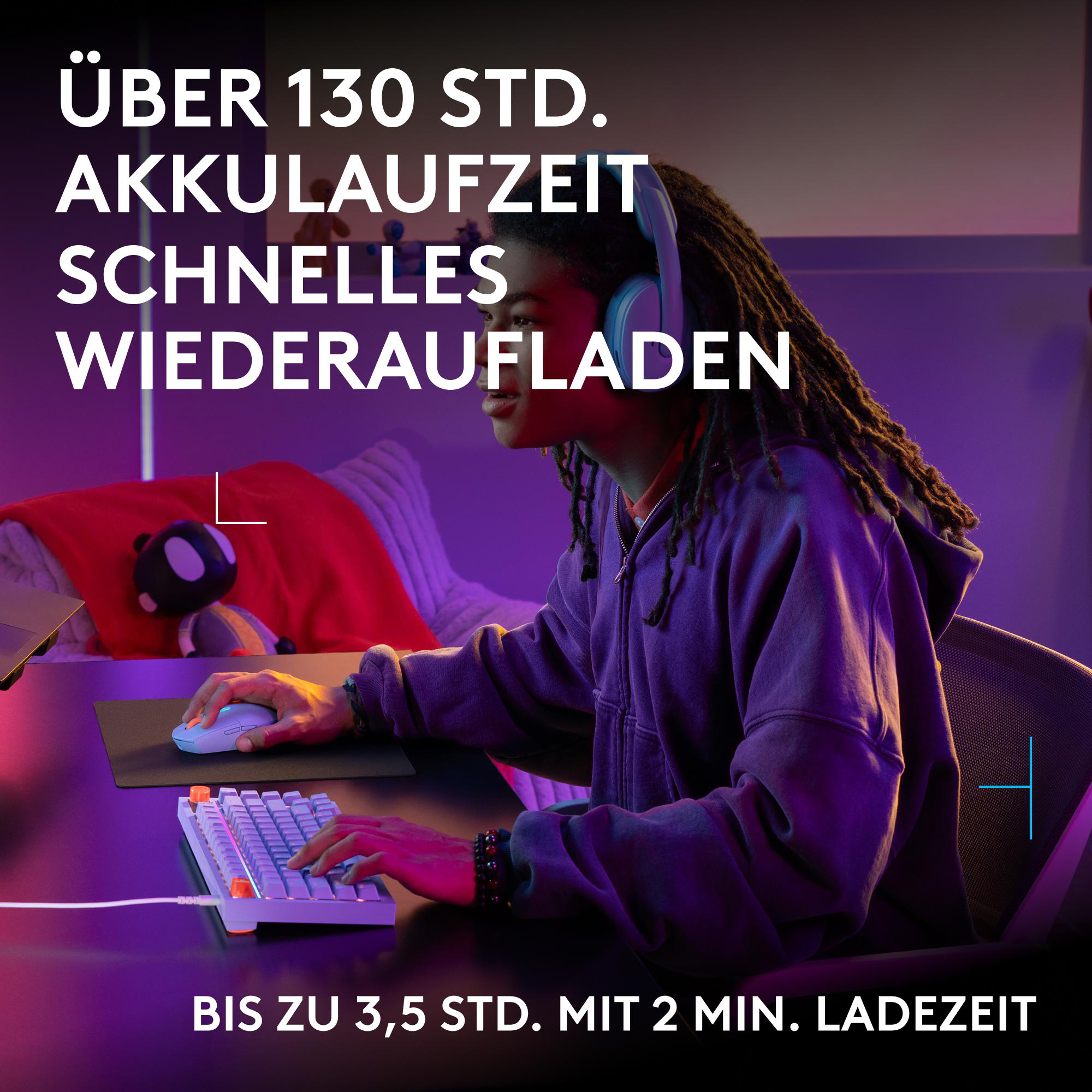 Ein junger Mann mit Dreadlocks sitzt an einem Schreibtisch und spielt in einem lilafarbenen Raum am Computer.