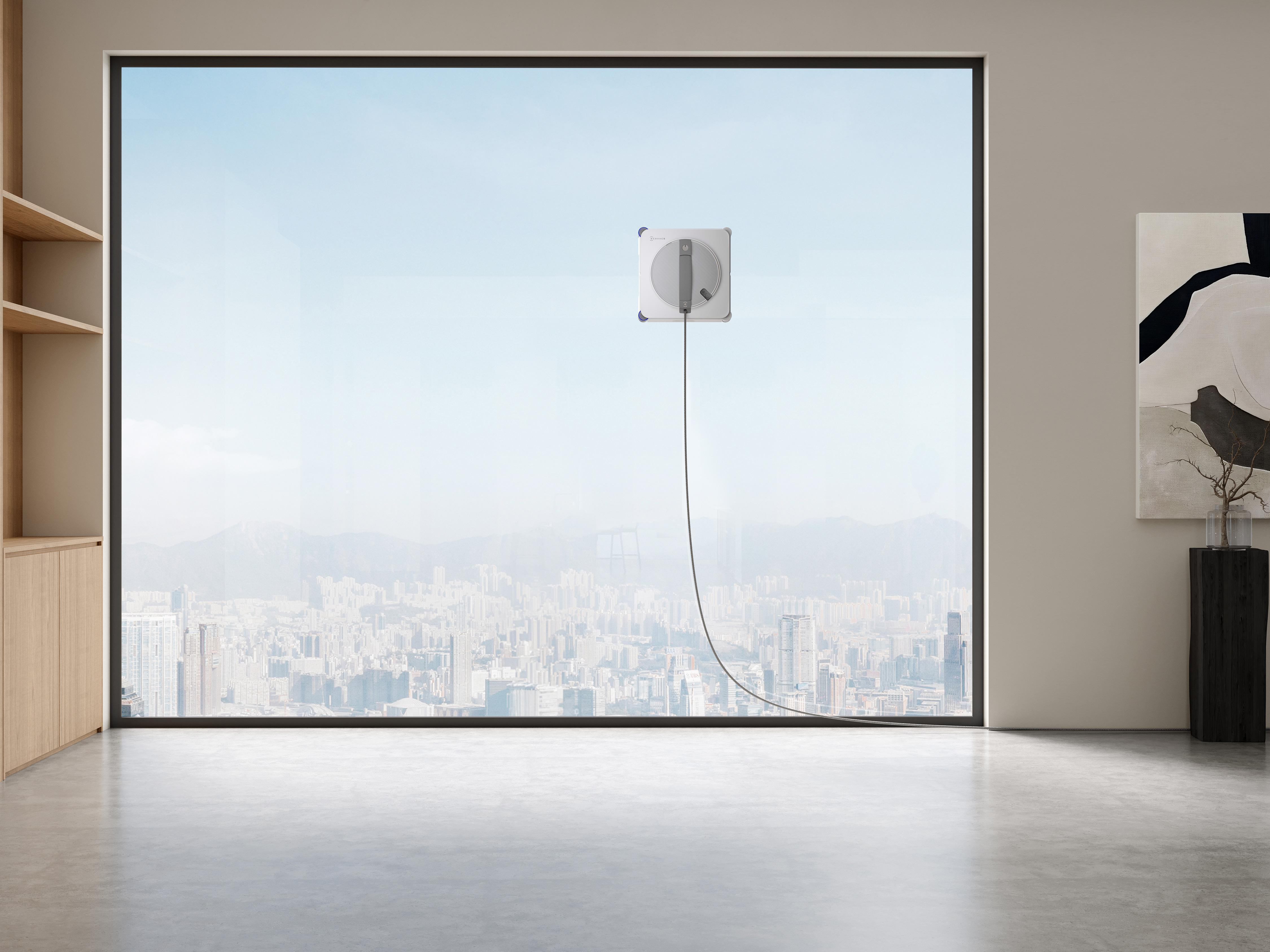 Ein automatischer Fensterputzer reinigt eine große Fensterscheibe mit Blick auf eine Stadt.