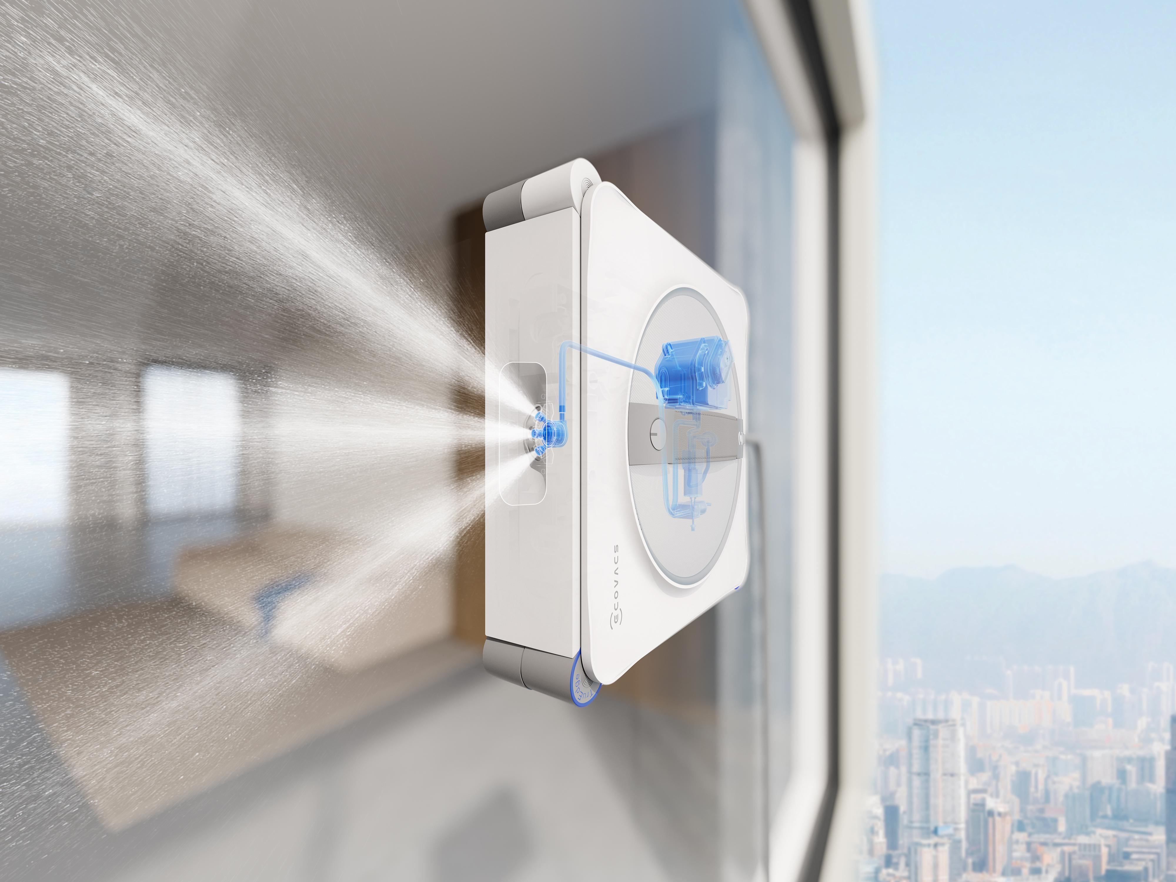 Ein weißer Fensterreinigungsroboter sprüht Wasser auf eine Fensterscheibe vor einer Stadtkulisse.