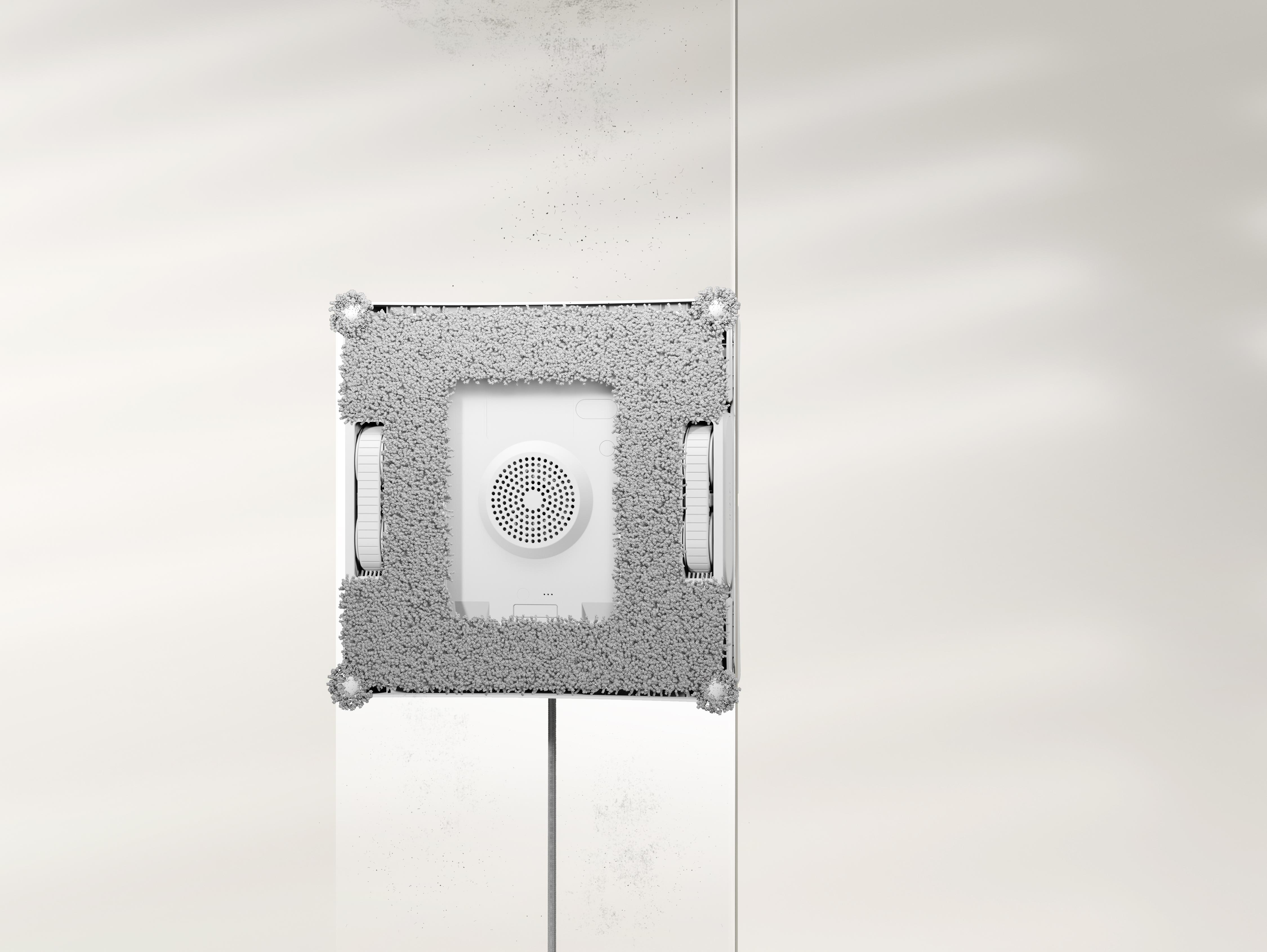Ein weißer, quadratischer Fensterreinigungsroboter saugt sich an eine weiße Glasfläche.