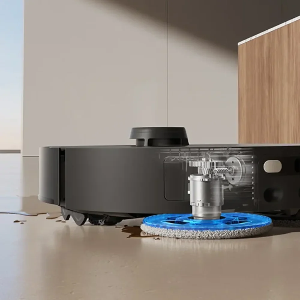 Egy fekete robotporszívó tisztítja a padlót, áttetszően mutatva a belső felmosó mechanizmusát.