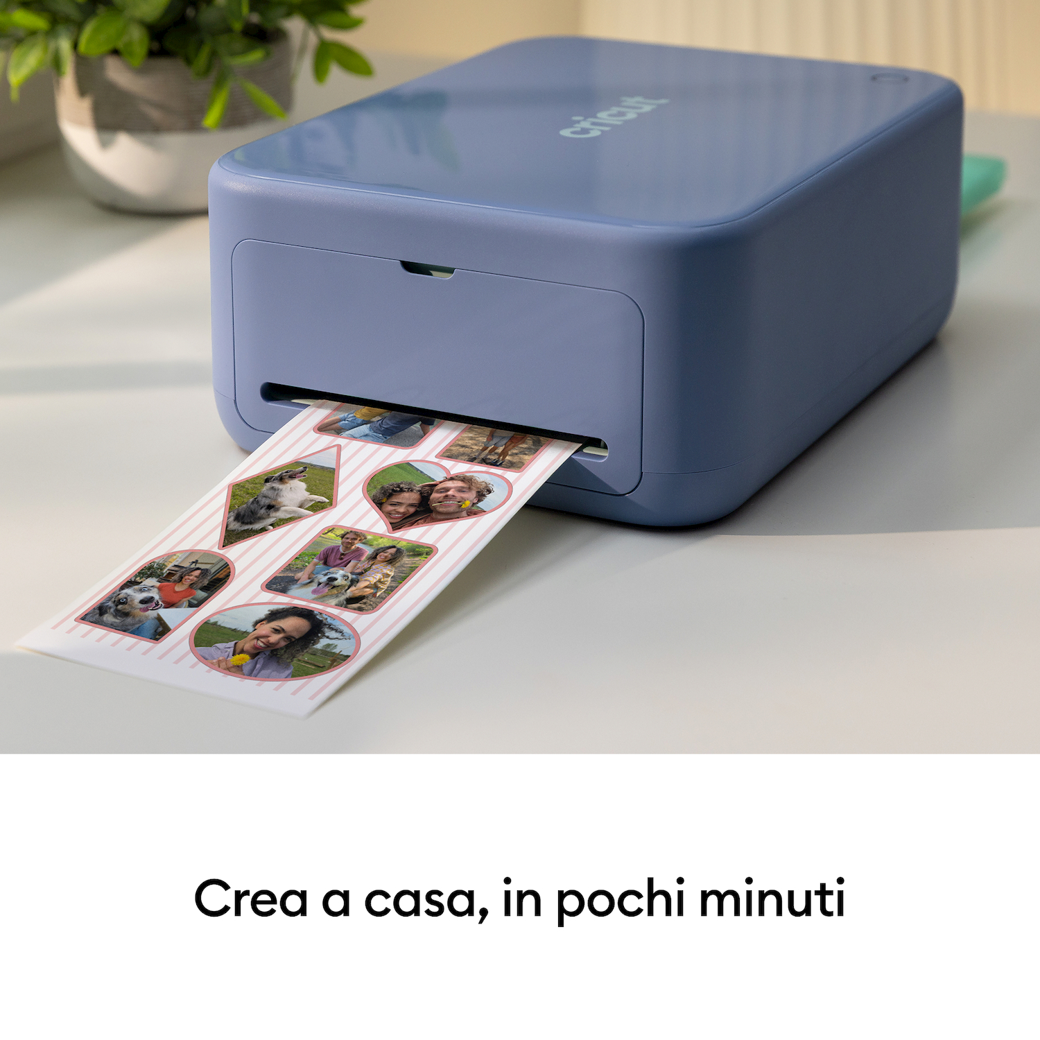 Una stampante Cricut blu stampa un foglio con piccole foto di persone e cani.