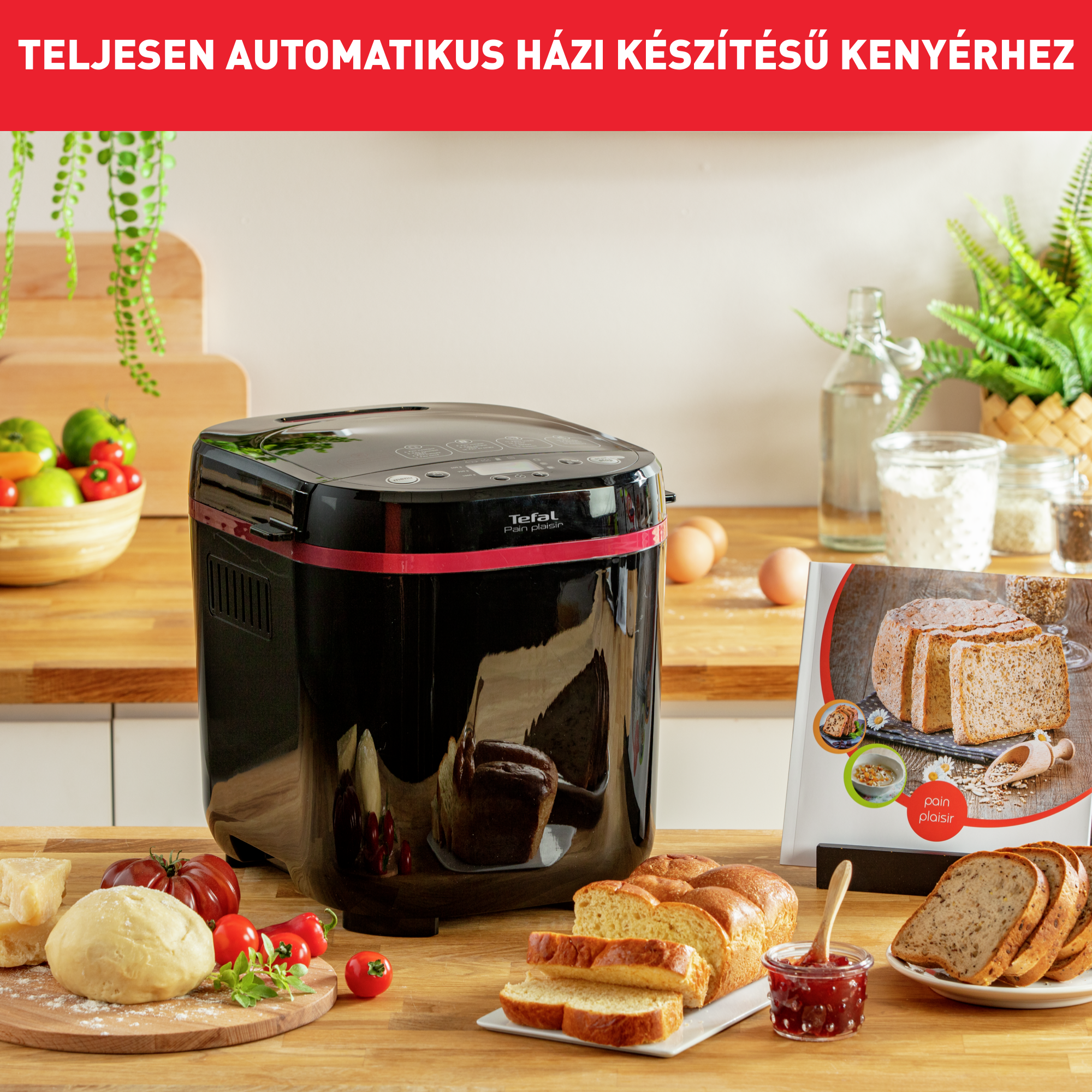 Fekete Tefal kenyérsütő fa asztalon tésztával, szeletelt kenyérrel, paradicsommal, lekvárral és receptkönyvvel.