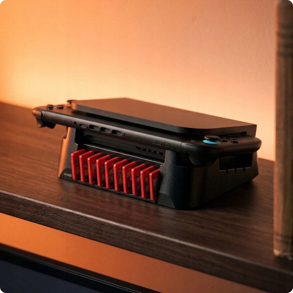 Konsola Nintendo Switch w czarnym uchwycie z czerwonymi kartami do gry na drewnianej półce.