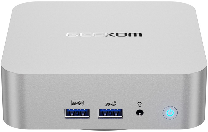 Egy ezüst Geekom mini PC elülső USB-portokkal, audiócsatlakozóval és világító bekapcsológombbal.