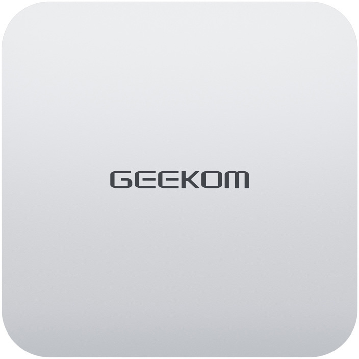 Egy ezüst színű Geekom mini PC lekerekített sarkokkal és középre helyezett logóval.