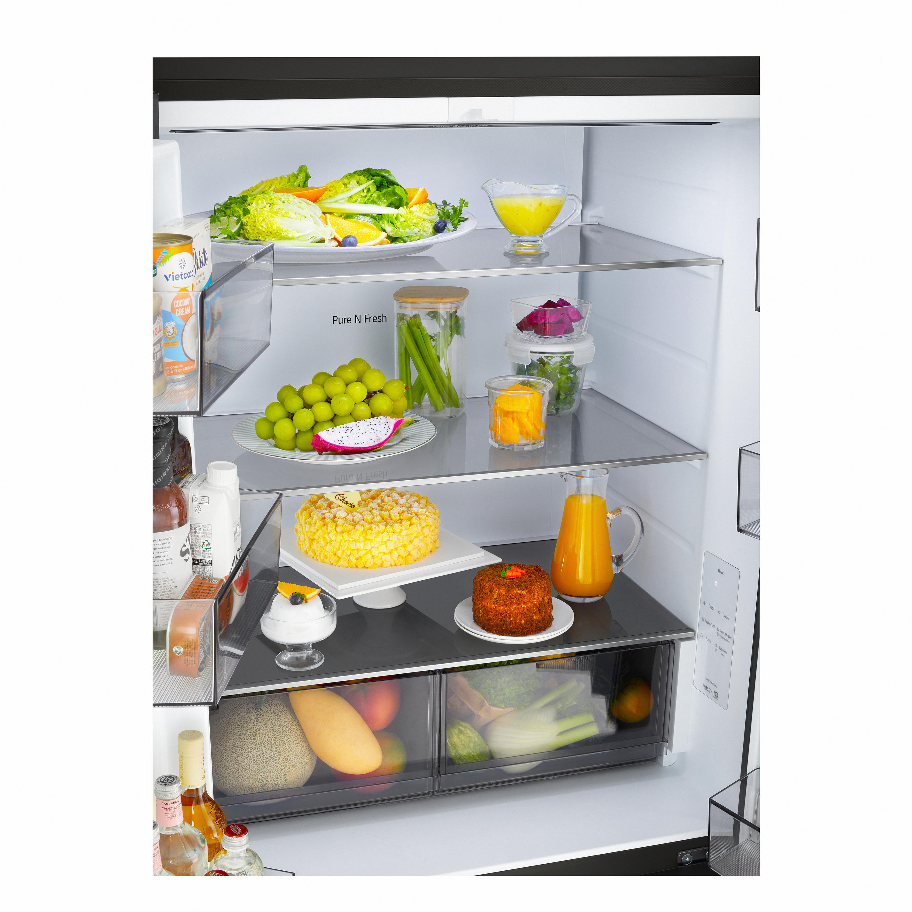 Ein gut gefüllter Kühlschrank mit frischem Obst, Salat, Kuchen, Säften und Gemüse in den Schubladen.