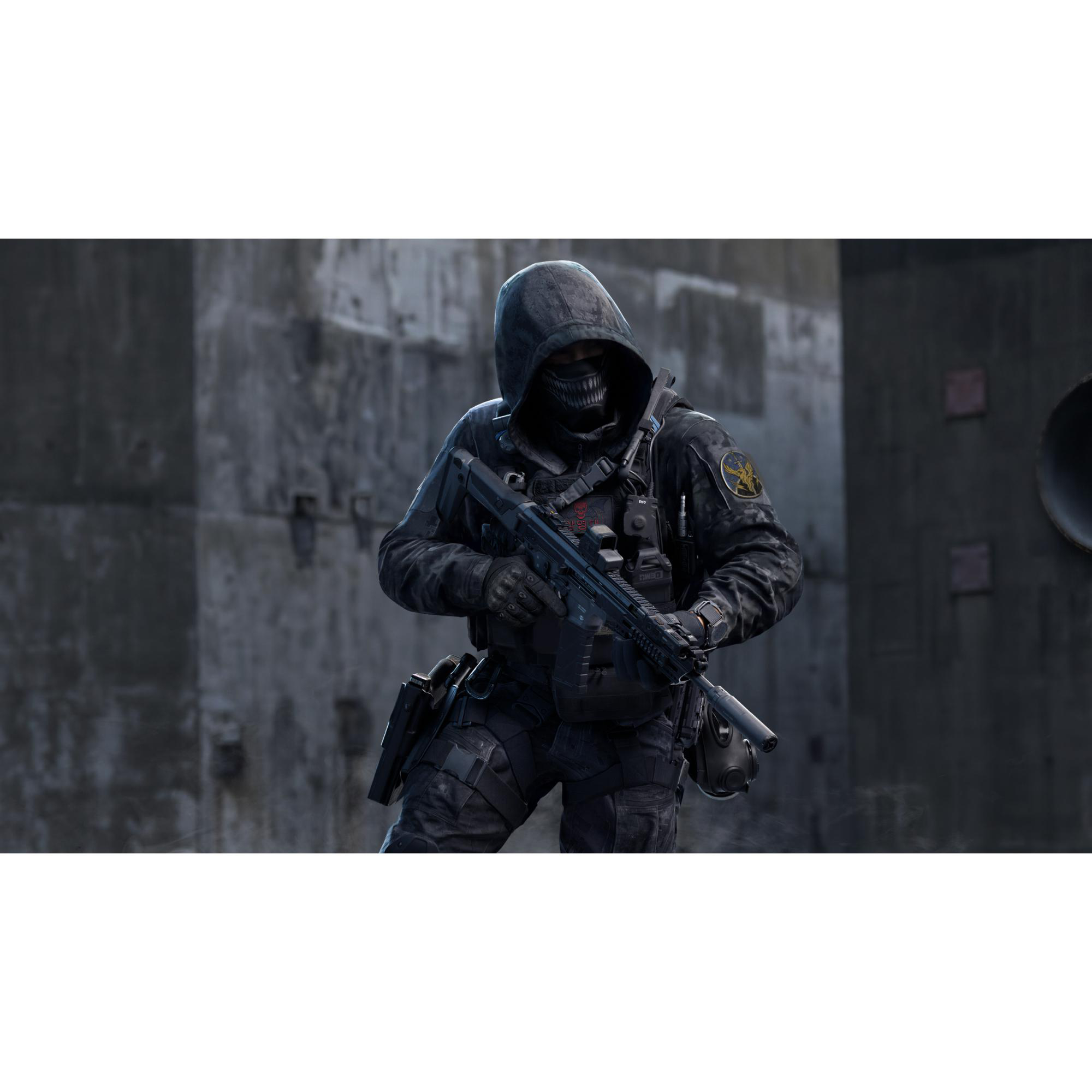 Ein Soldat in dunkler Kampfausrüstung mit Kapuze und Maske hält ein Sturmgewehr vor einer Betonwand.