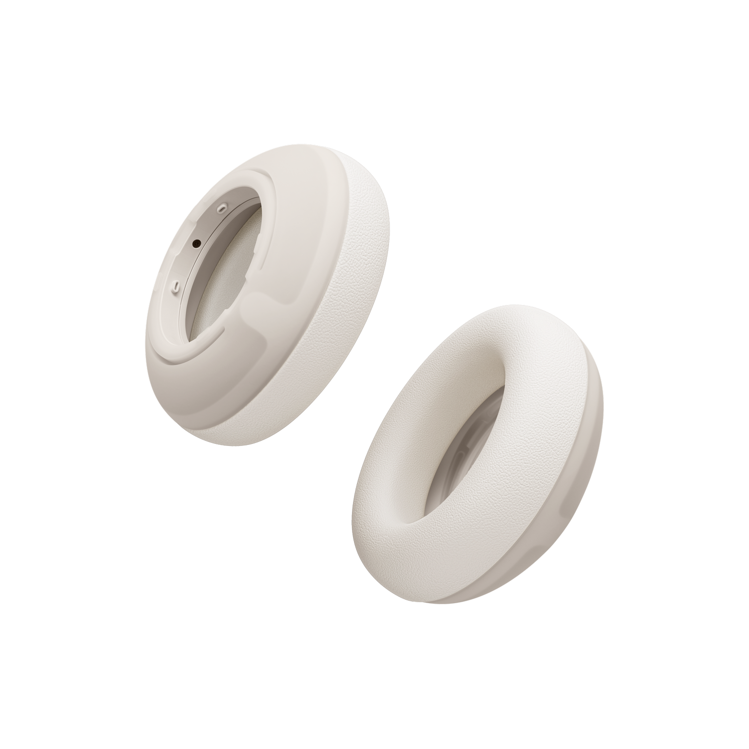 Dos almohadillas de auriculares de color crema flotan sobre fondo negro.