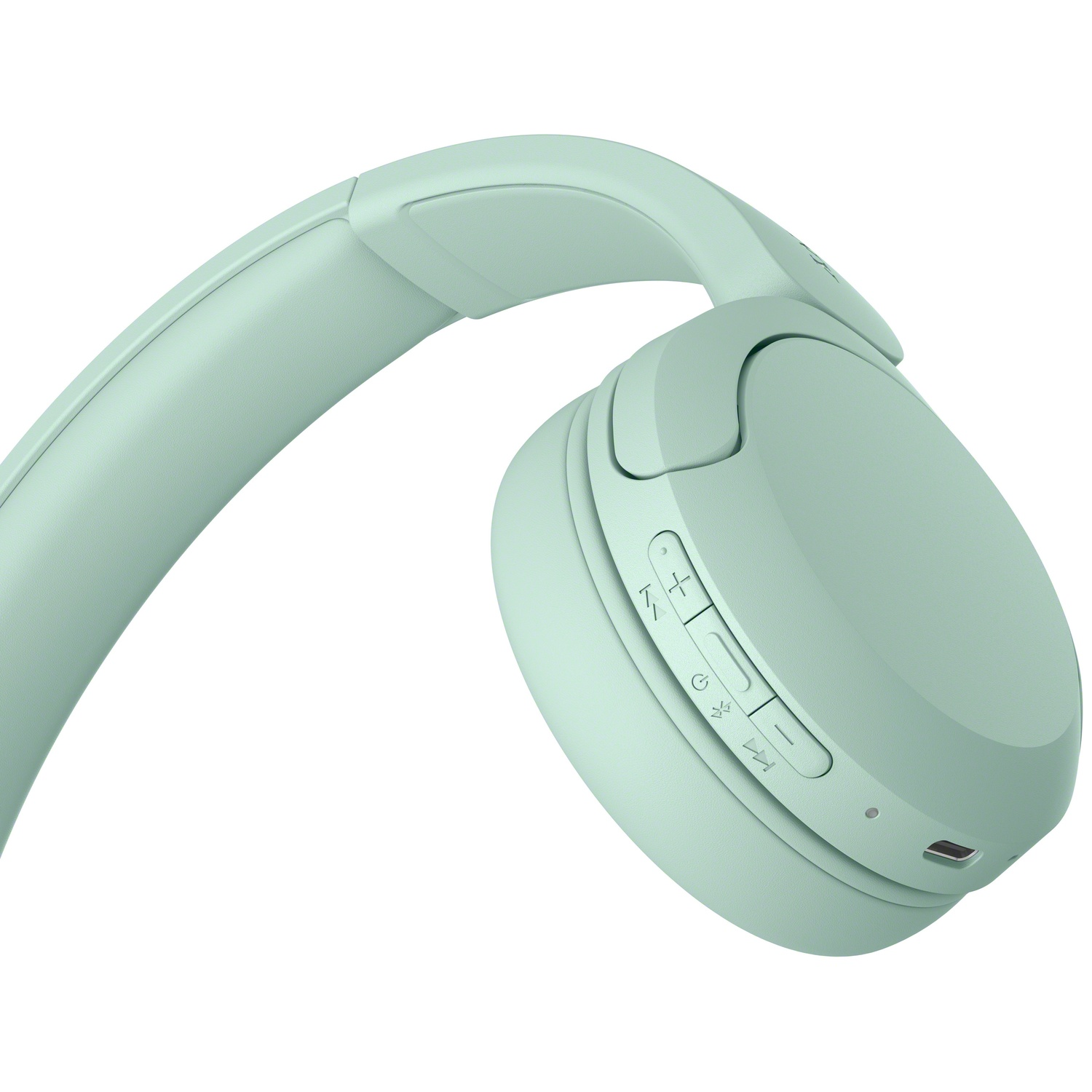 Gros plan d'un casque sans fil vert menthe montrant les boutons de contrôle et le port de charge.