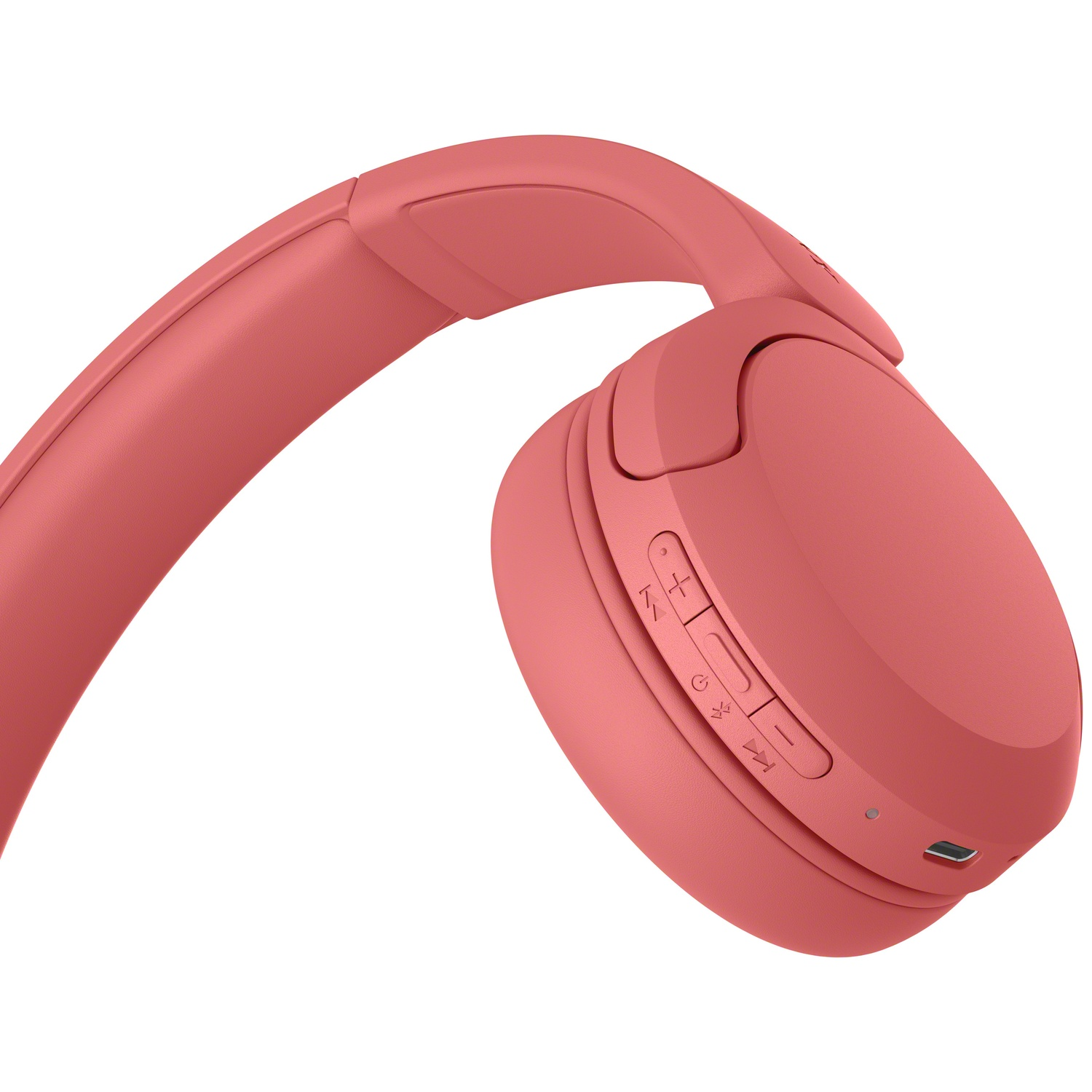 Gros plan d'un casque sans fil rose avec boutons de commande et port de charge sur fond blanc.