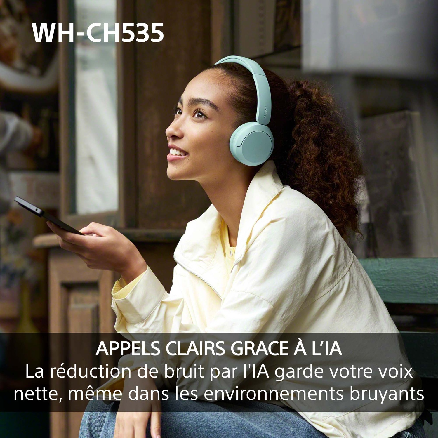 Une femme portant un casque bleu et une chemise claire tient un smartphone.