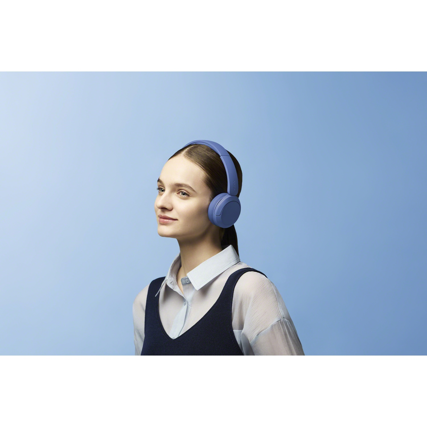 Une jeune femme portant un casque bleu pose devant un fond bleu.